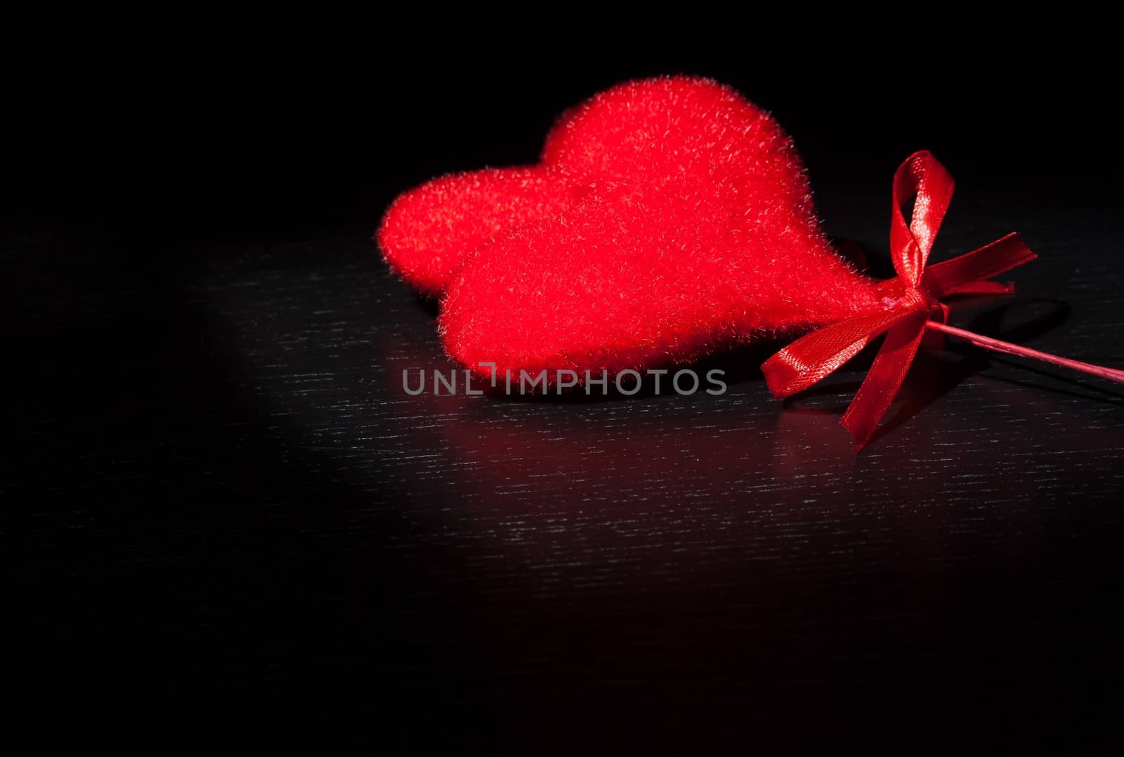 two decorative velvet red hearts on black dark light and on wood table, concept of valentine day by donfiore