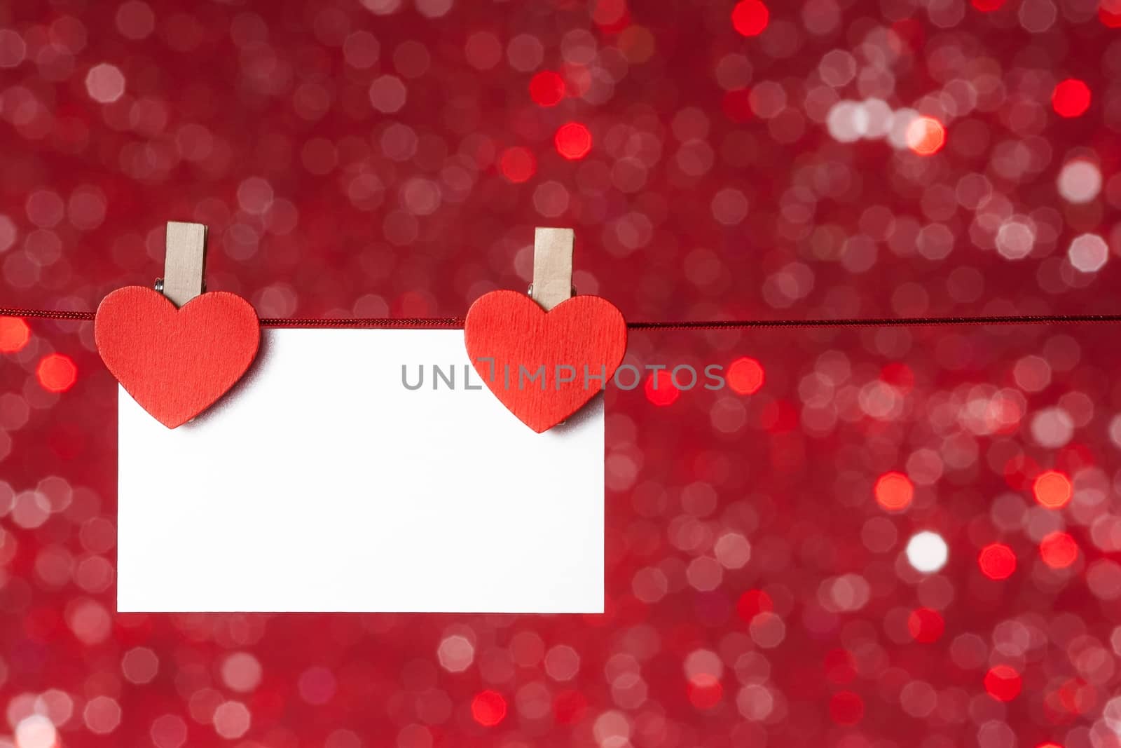 two decorative red hearts with greeting card hanging on red light bokeh background, concept of valentine day by donfiore