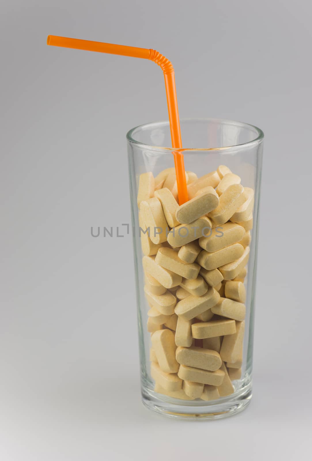 Conceptual vitamin drink with orange straw
