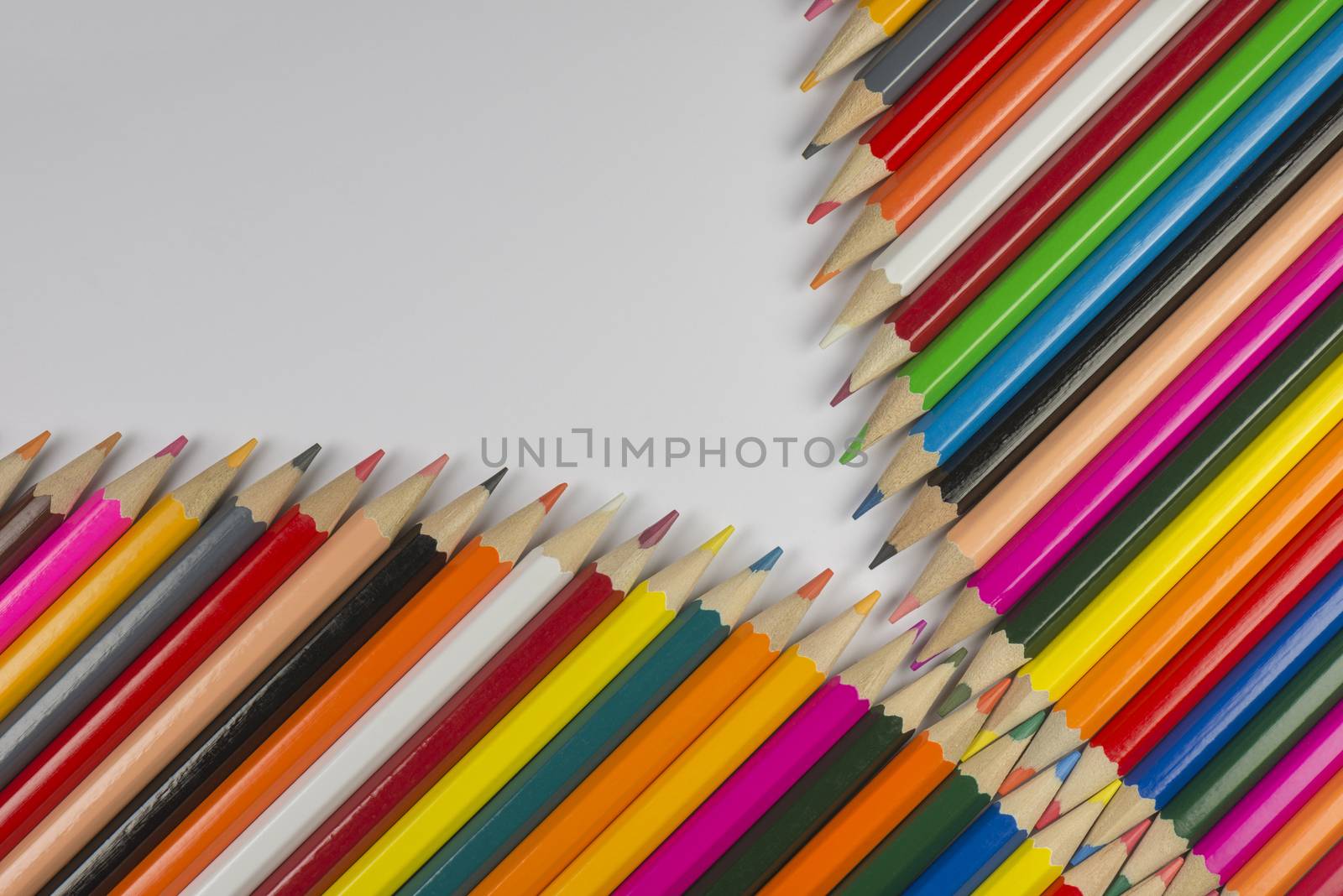 Abstract composition of a set cedar wooden colour pencils against a white background in zipper style

