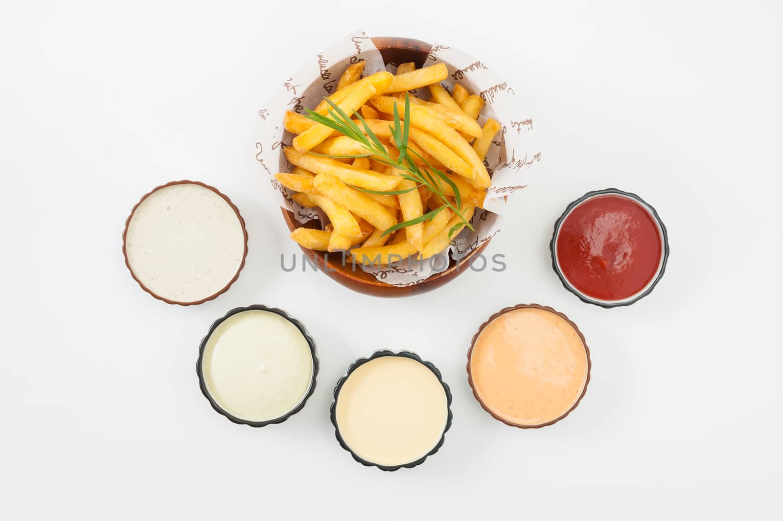 French fries in wood bowl garnished with Japanese bamboo leaves with 5 sauce tartar sauce, wasabi mayo sauce, mayonnaise, thousand island sauce, and ketchup