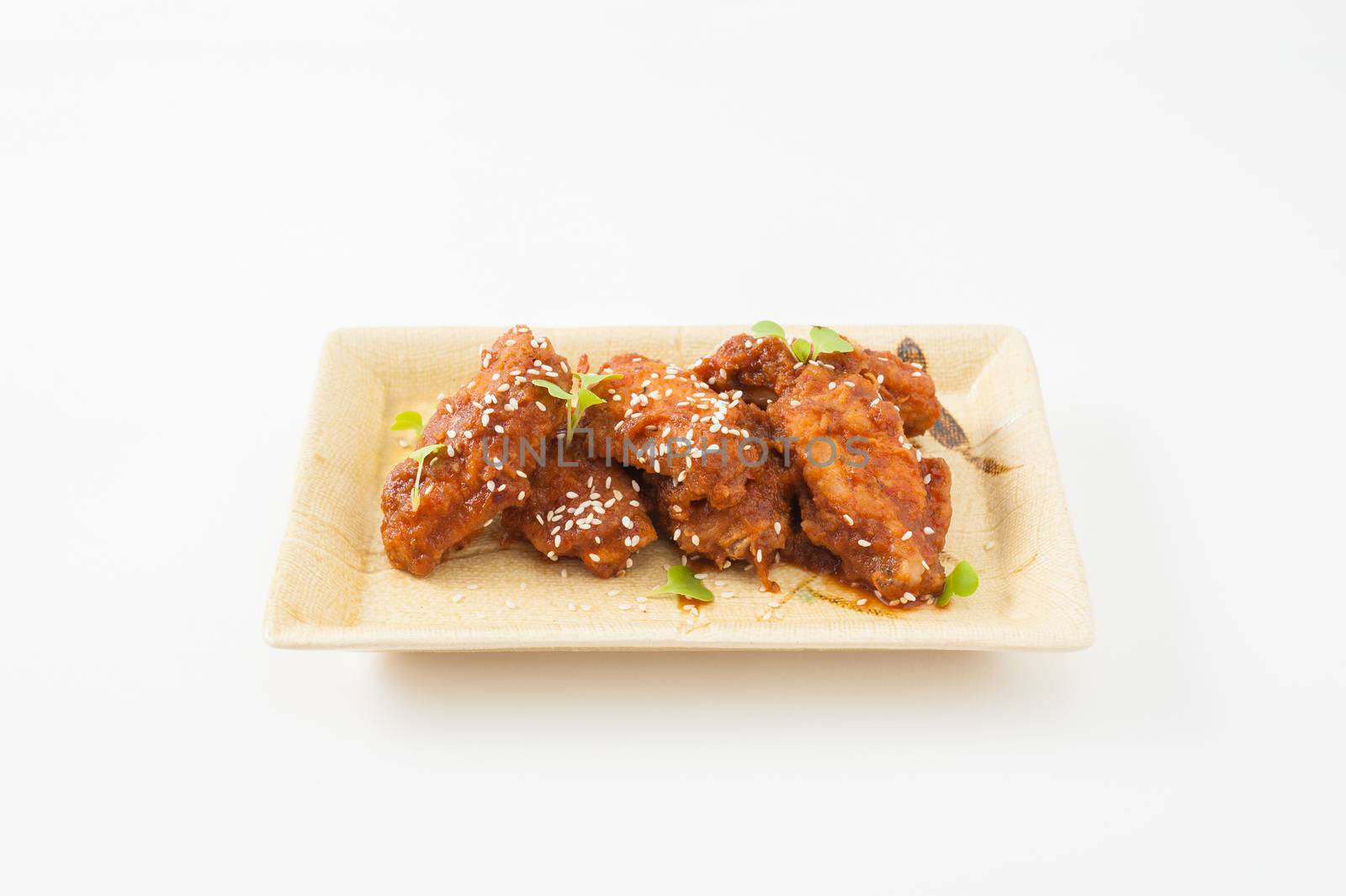 Korean fusion style deep fried chicken wings seasoned with Korean spicy kimchi sauce on square ceramic dish