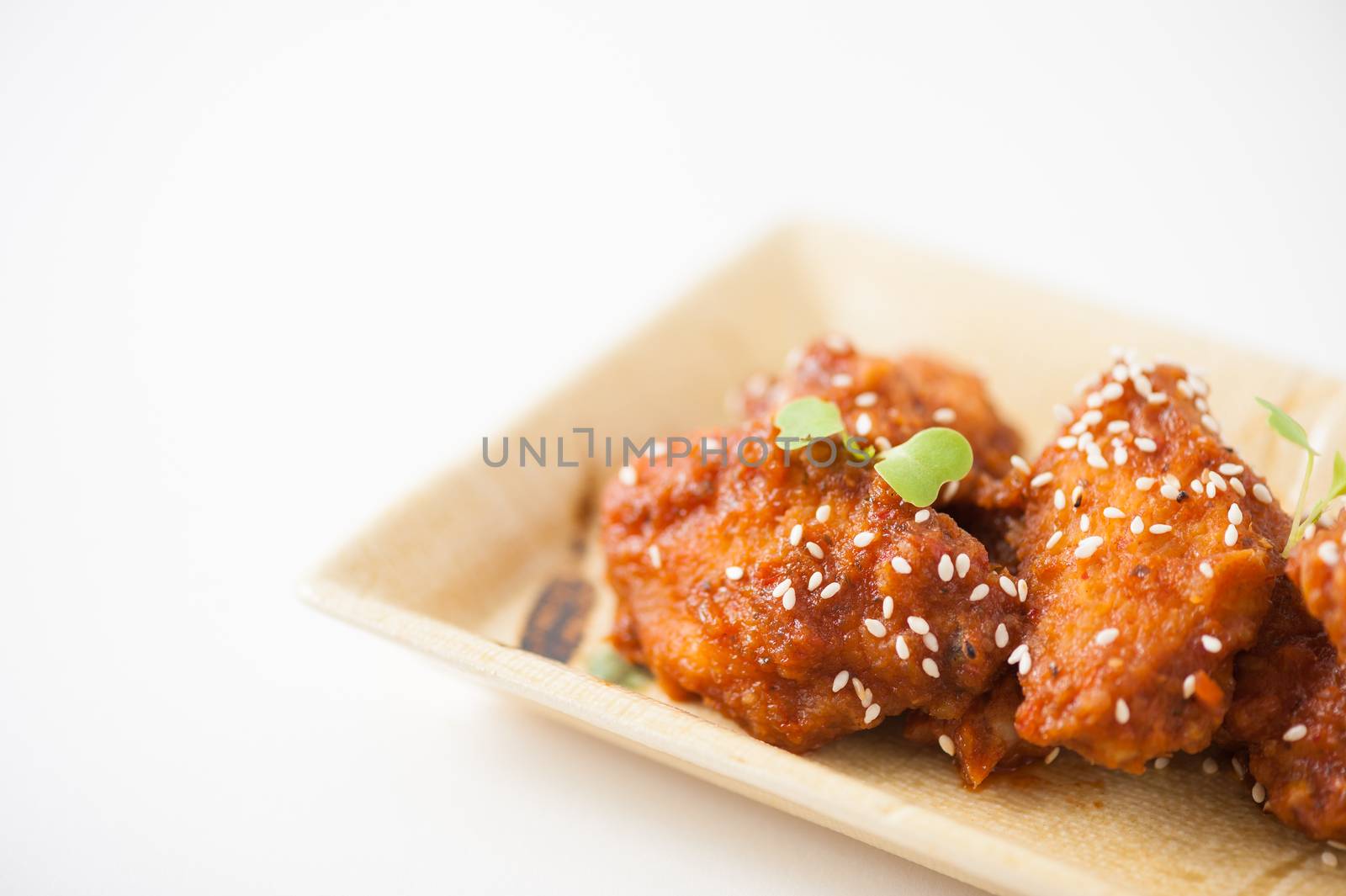 Korean fusion style deep fried chicken wings seasoned with Korean spicy kimchi sauce on square ceramic dish