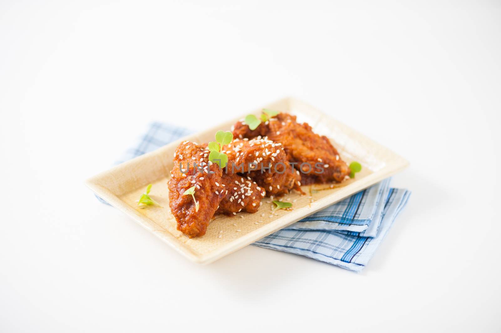 Korean fusion style deep fried chicken wings seasoned with Korean spicy kimchi sauce on square ceramic dish