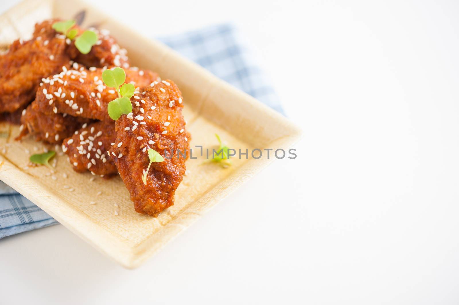 Korean fusion style deep fried chicken wings seasoned with Korean spicy kimchi sauce on square ceramic dish