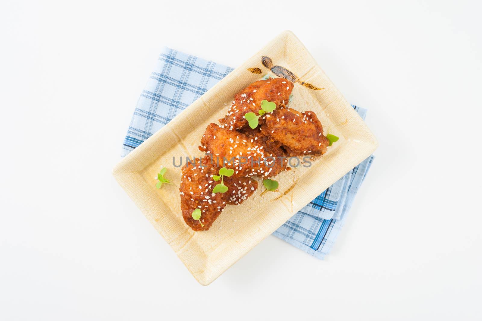 Korean fusion style deep fried chicken wings seasoned with Korean spicy kimchi sauce on square ceramic dish