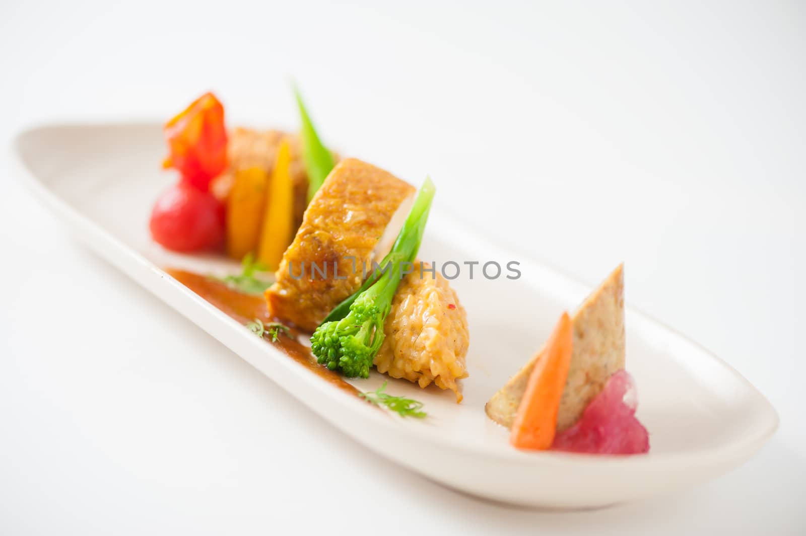 3 modern cuisine Prosciutto Wrapped Chicken with resotto and tamarind sauce, Fried mussaman curry, and Thai chicken spicy sausage on ceramic dish garnished with vegetables