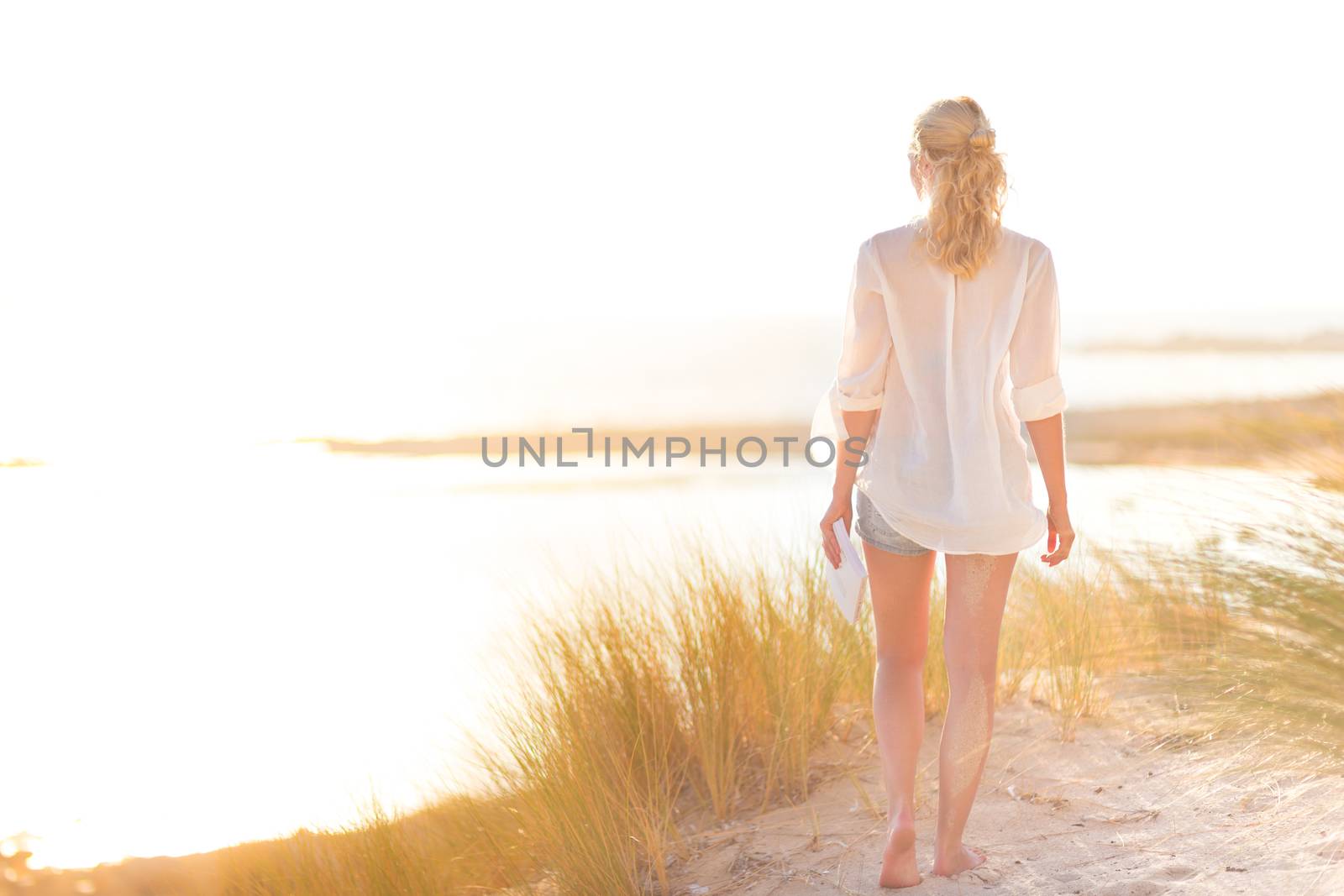 Relaxed woman enjoying freedom and life an a beautiful sandy beach.  Young lady feeling free, relaxed and happy. Concept of happiness, enjoyment and well being.  Enjoying Sun on Vacations. Copyspace.