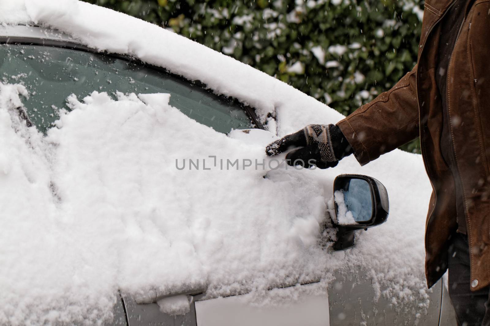 Man scraping snow and ice from car window