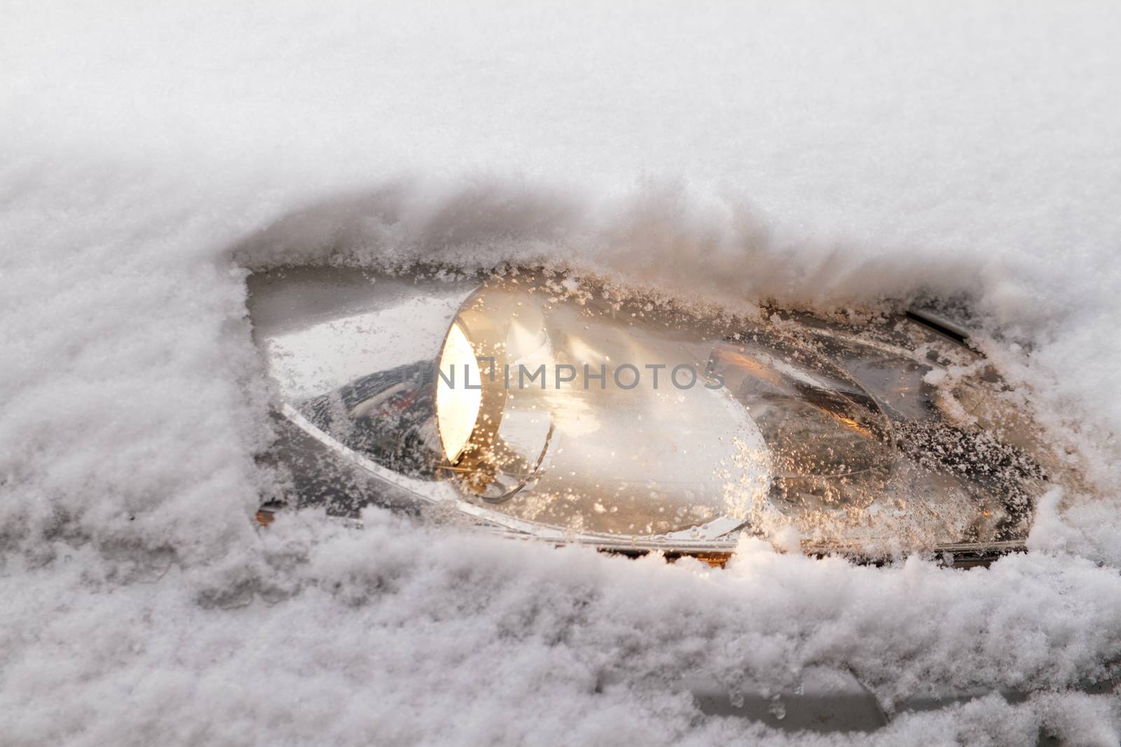 Photo of a snowy car's snowy headlight 