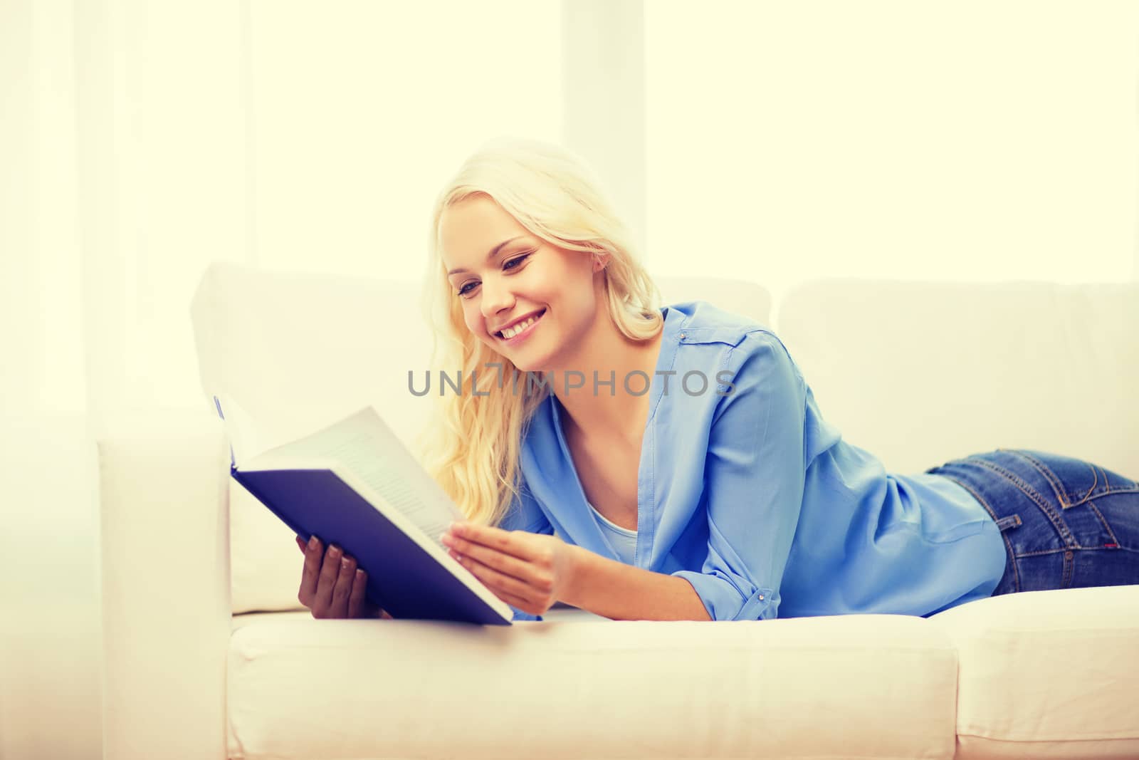 smiling woman reading book and lying on couch by dolgachov