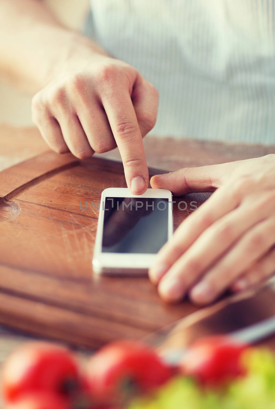 cooking, technology and home concept - closeup of man pointing finger to smartphone