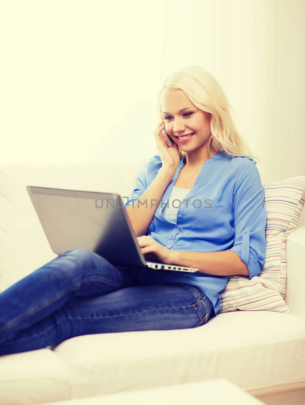 home, technology and internet concept - smiling woman with smartphone and laptop computer sitting on couch at home