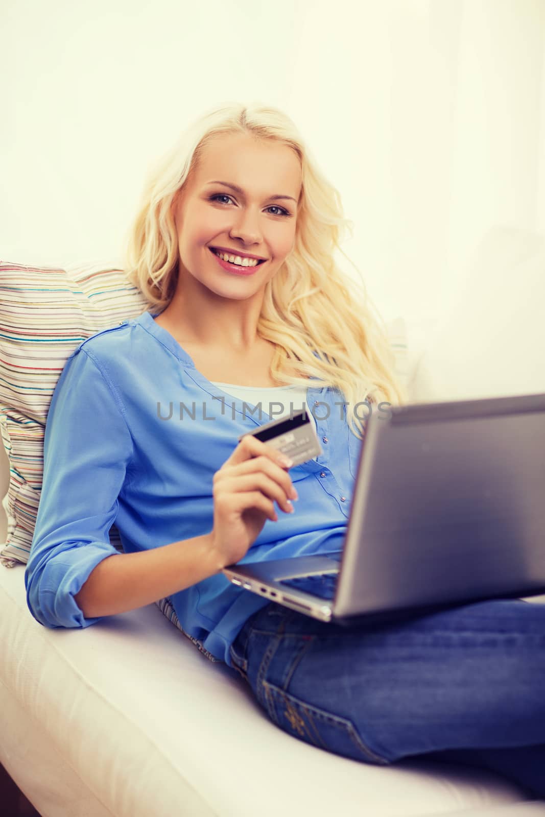 smiling woman with laptop computer and credit card by dolgachov