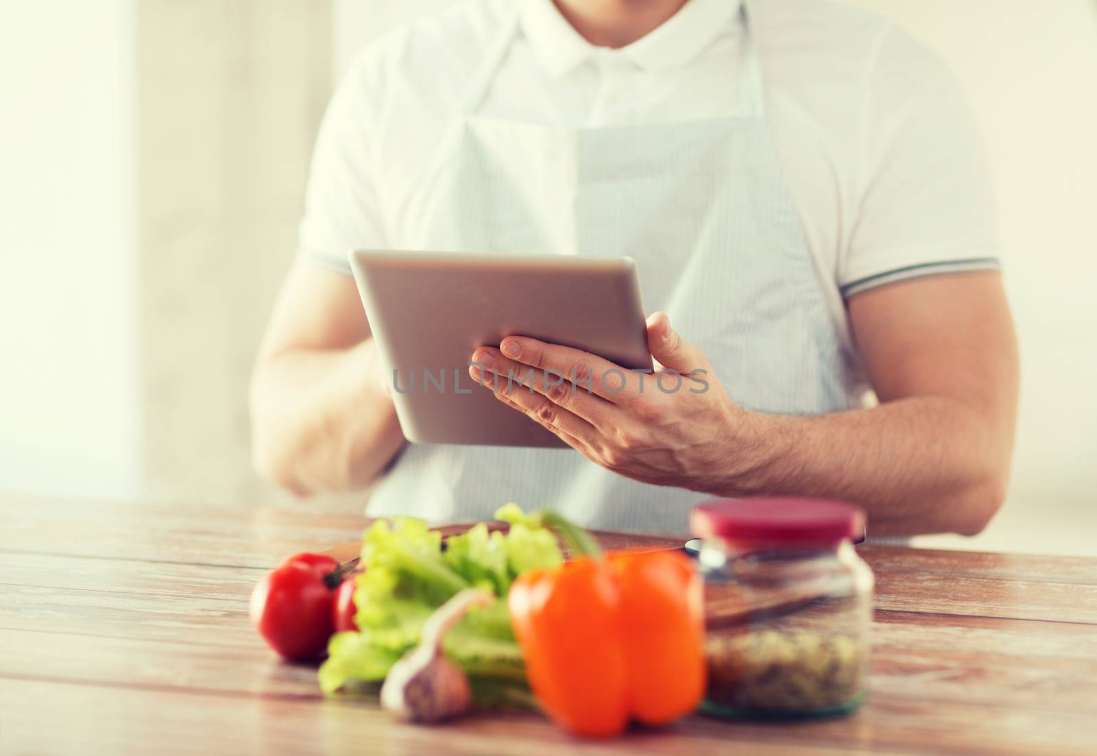 cooking, technology and home concept - closeup of man reading recipe from tablet pc computer