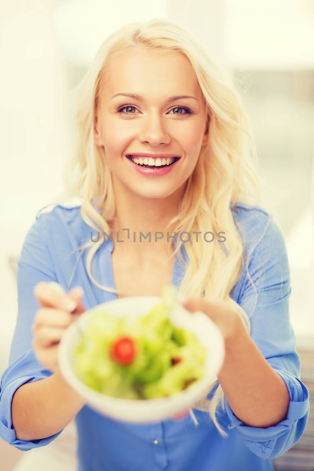 smiling young woman with green salad at home by dolgachov