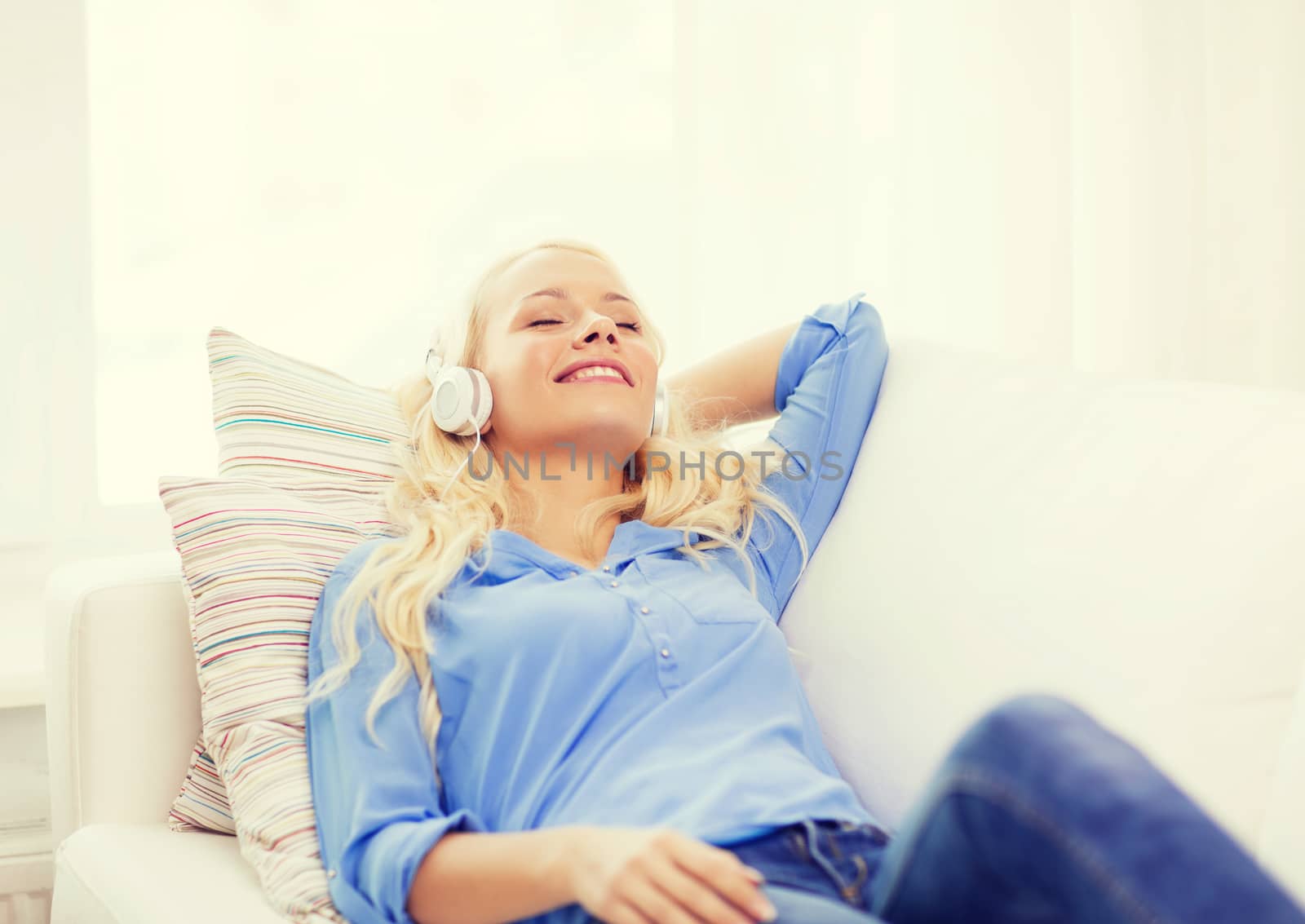 smiling young girl in headphones at home by dolgachov