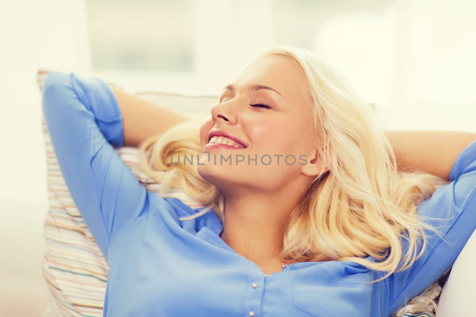 smiling young woman lying on sofa at home by dolgachov