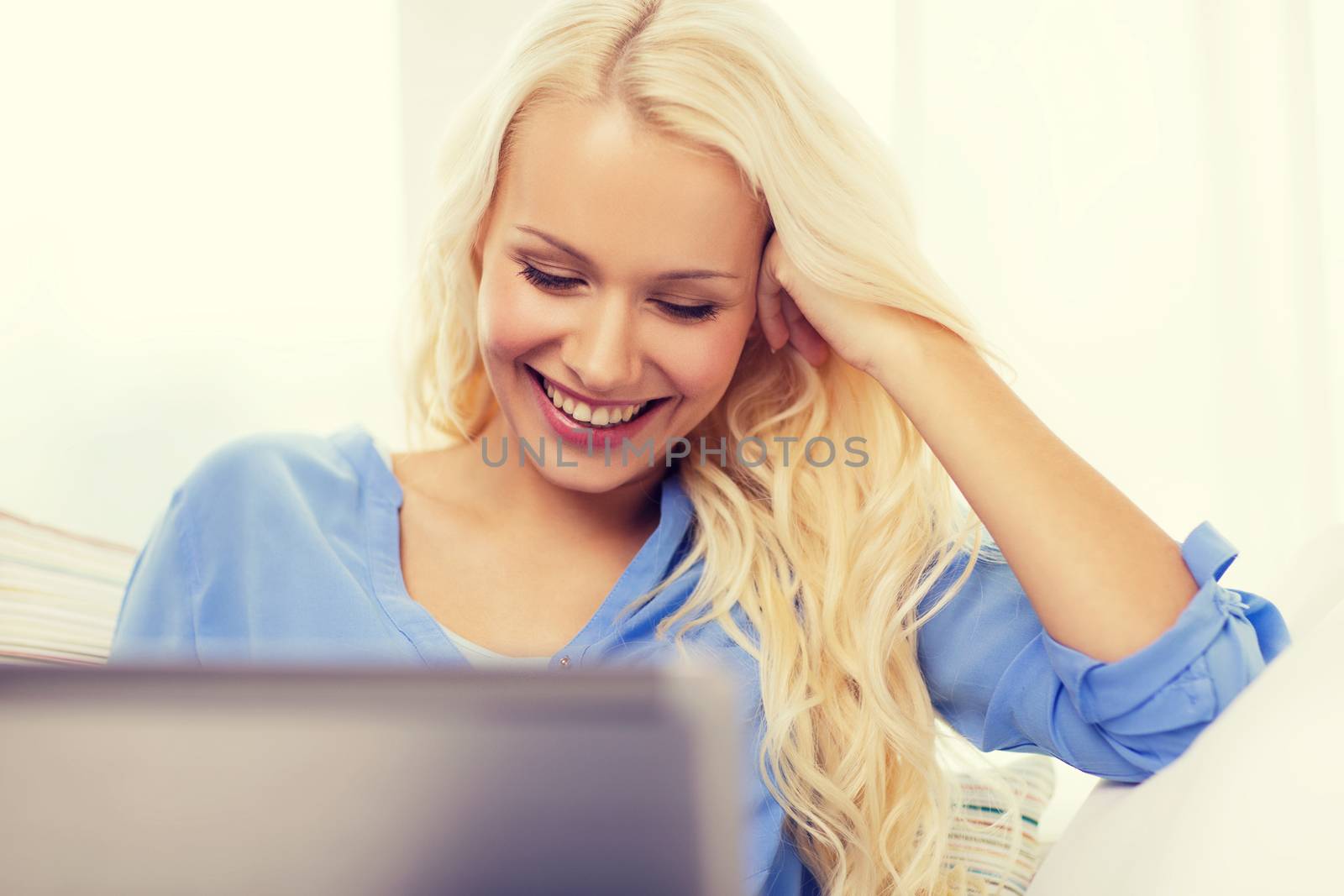 home, technology and internet concept - smiling woman sitting on the couch with laptop computer at home