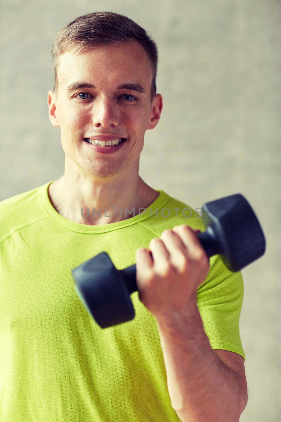 smiling man with dumbbell in gym by dolgachov