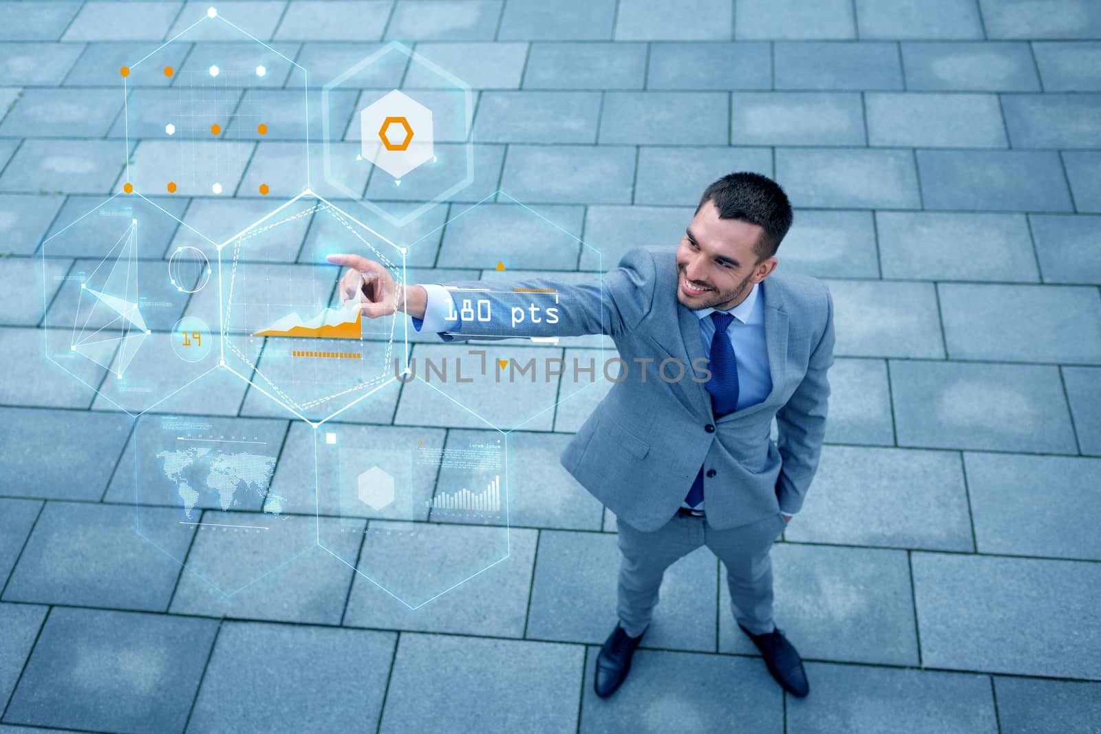 business, development, technology and people concept - young smiling businessman pointing finger to virtual screens with chart projection outdoors from top