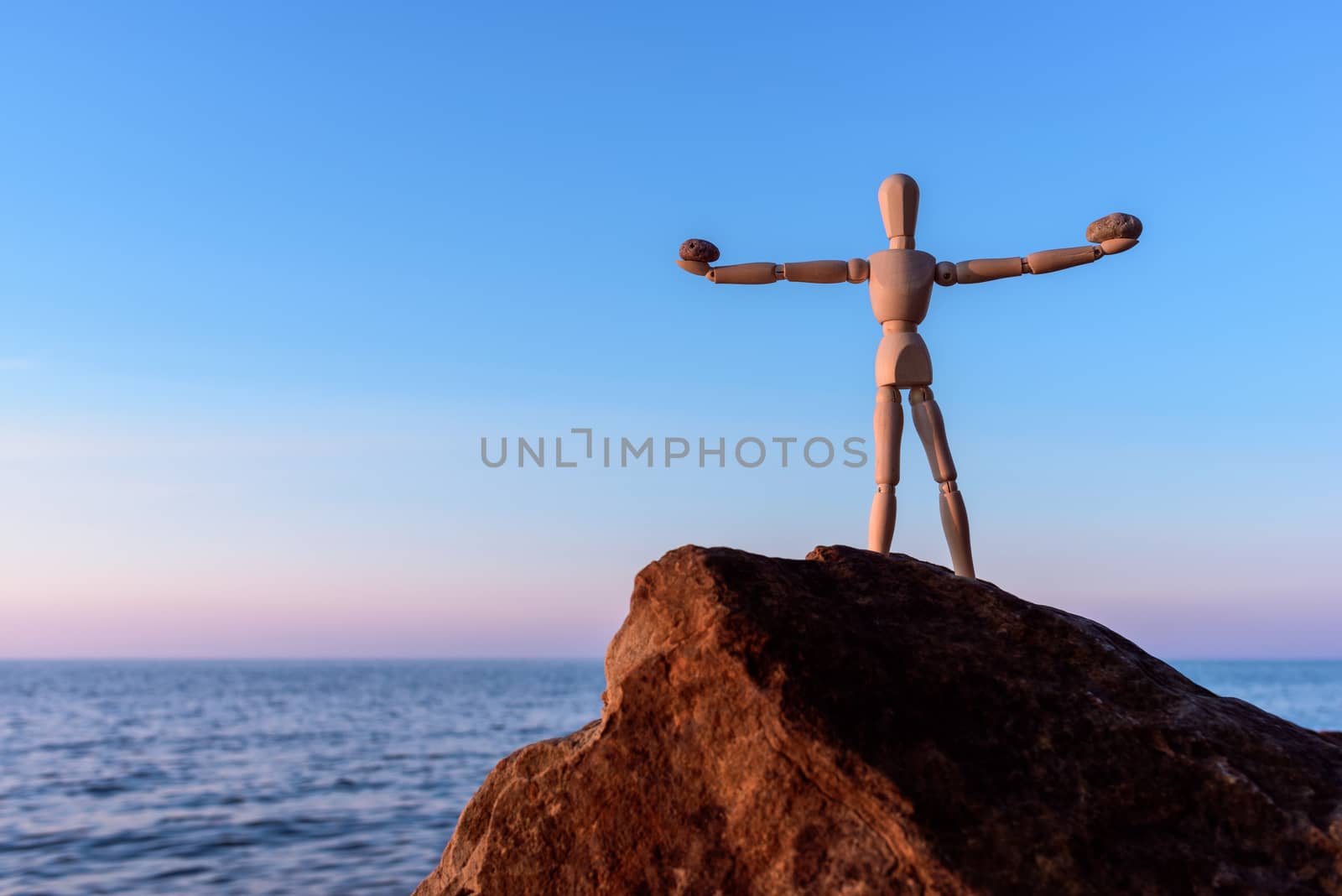 Wooden mannequin on the top of boulder