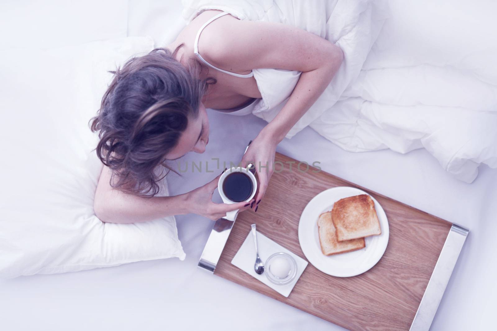 Beautiful young woman having breakfast in bed