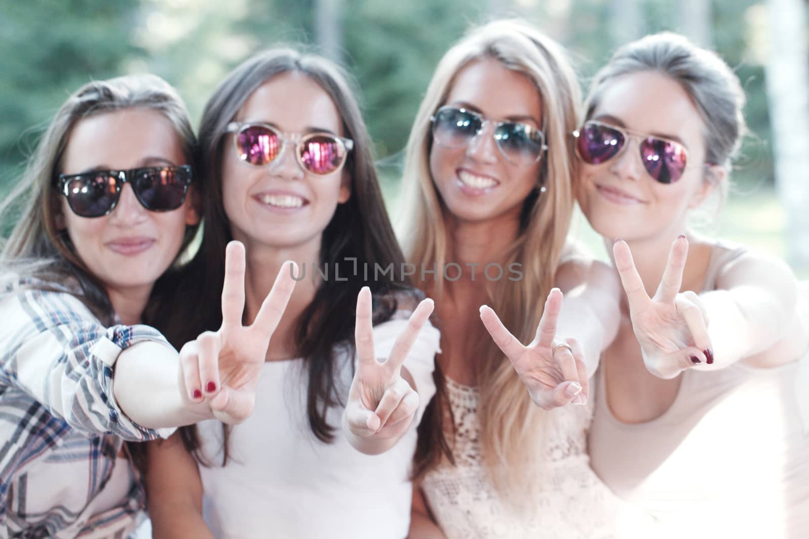 Happy smiling girlfriends showing a v hand sign