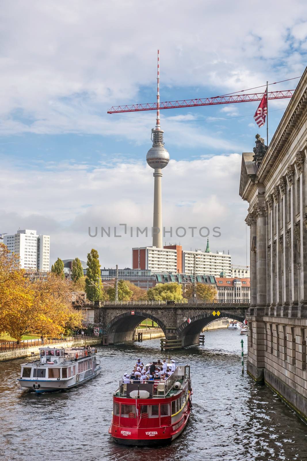 Berlin, Germany - October 26, 2013: Tourist boats on the Spree river - famous TV tower on Alexanderplatz square in the background.