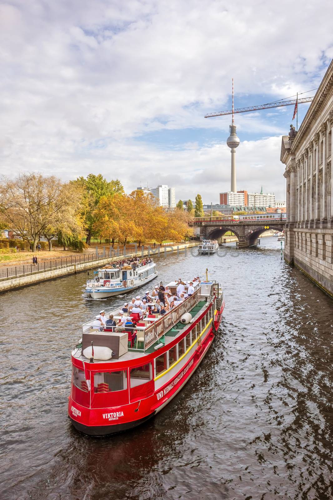 Berlin, Germany - October 26, 2013: Tourist boats on the Spree river - famous TV tower on Alexanderplatz square in the background.