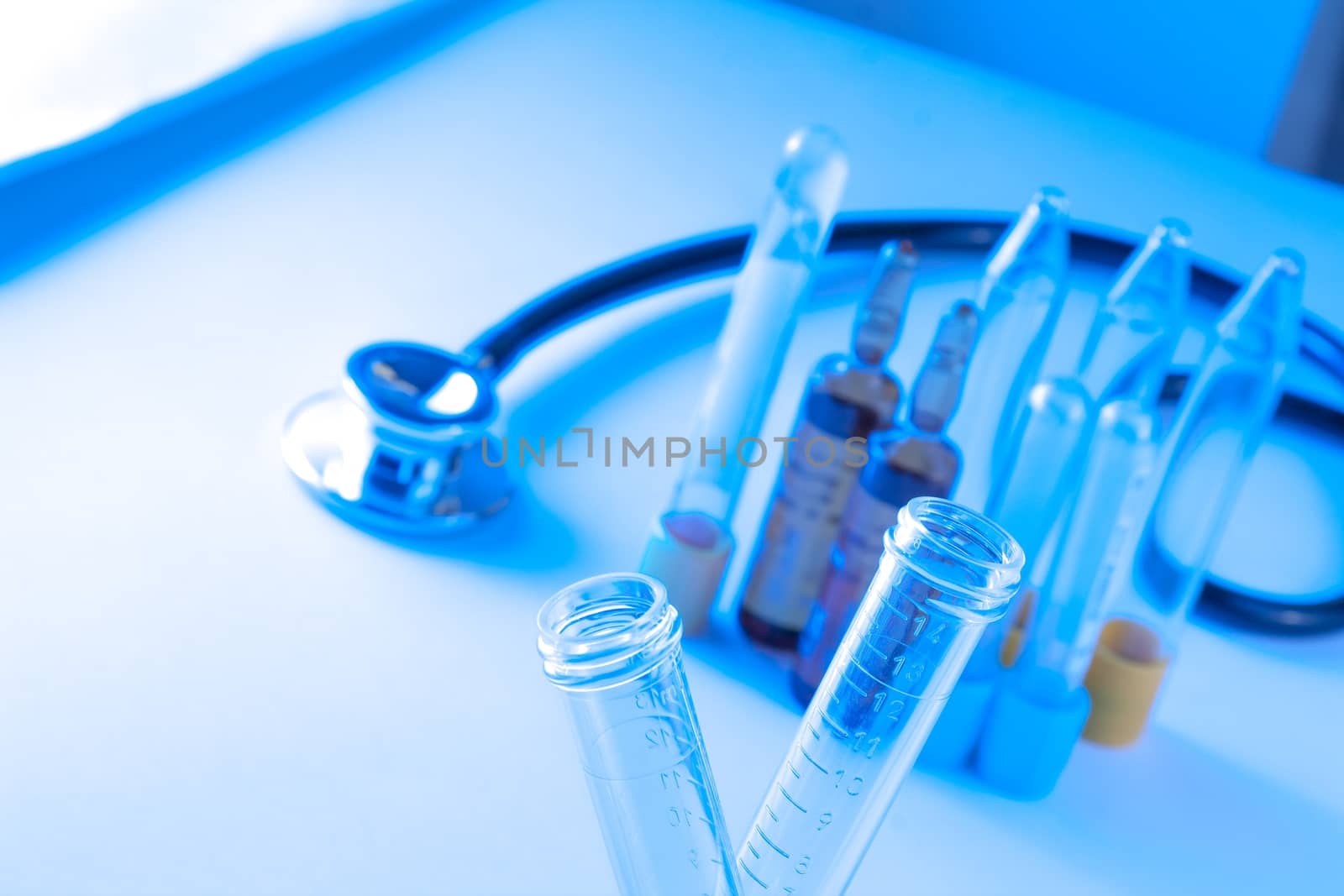 detail of test tubes in laboratory near stethoscope on blue light tint background