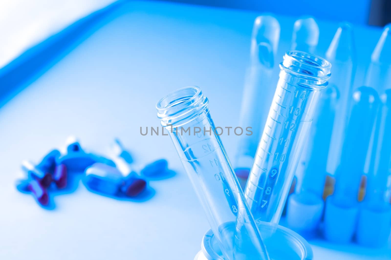 detail of test tubes in laboratory near pills on blue light tint background