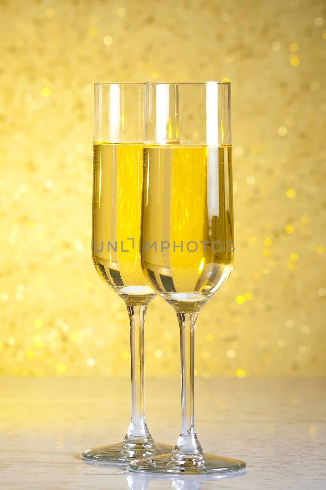 a pair of flutes of champagne on golden abstract background by donfiore