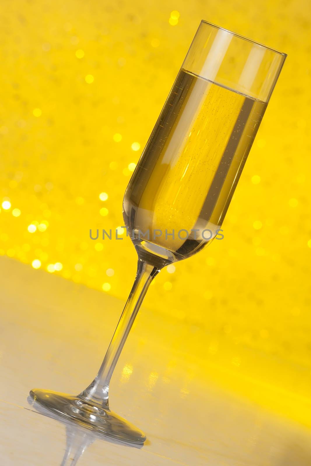 tilted flute of golden champagne on golden bokeh background