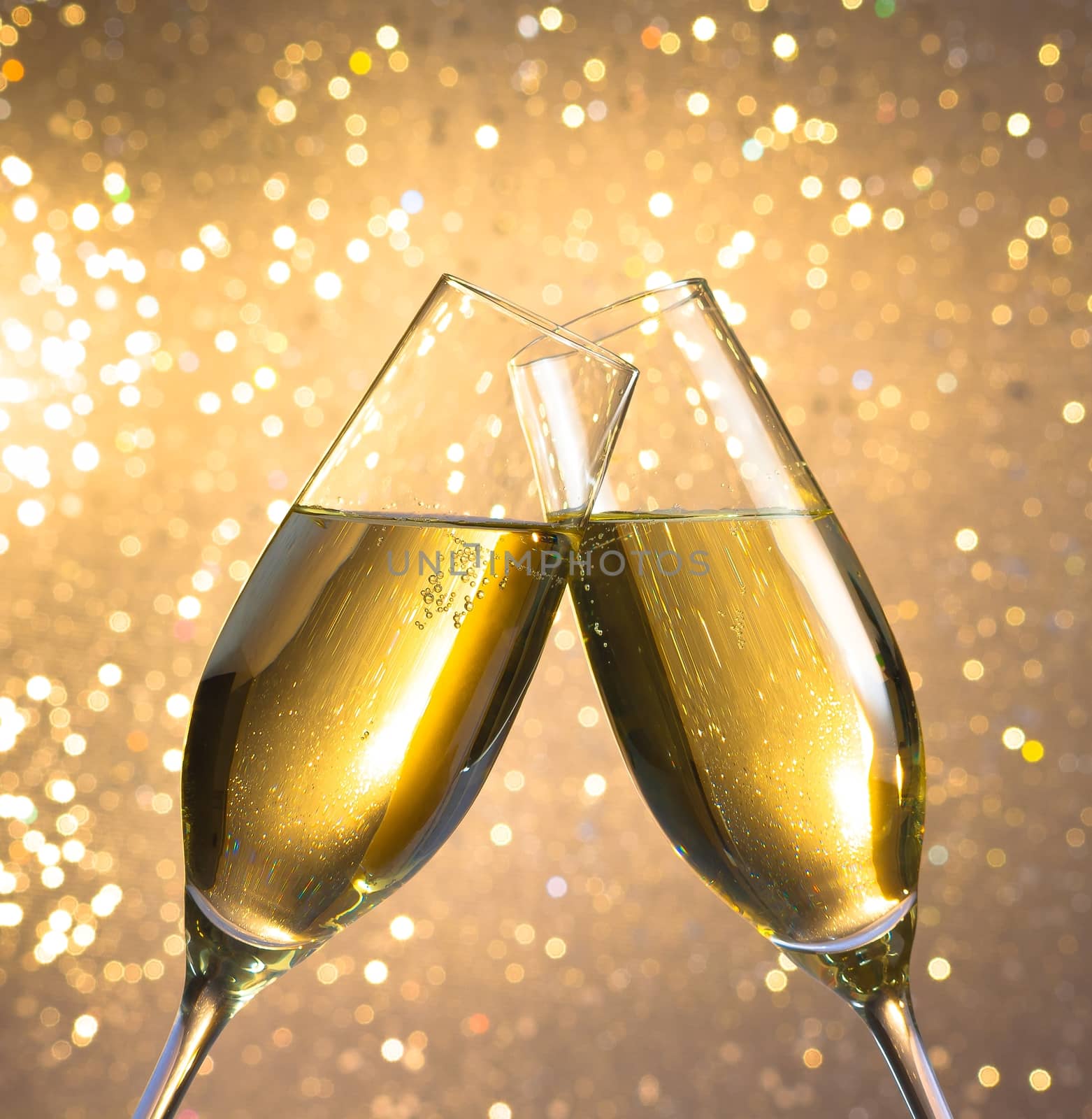 champagne flutes with golden bubbles on light bokeh background by donfiore