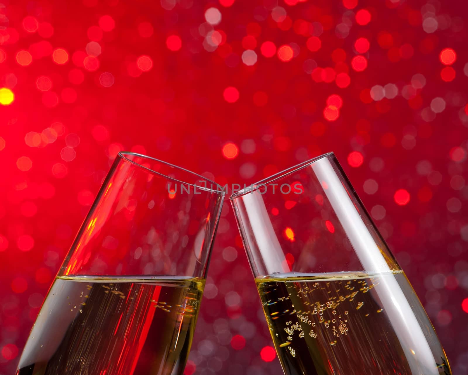 champagne flutes with gold bubbles on red light bokeh background by donfiore