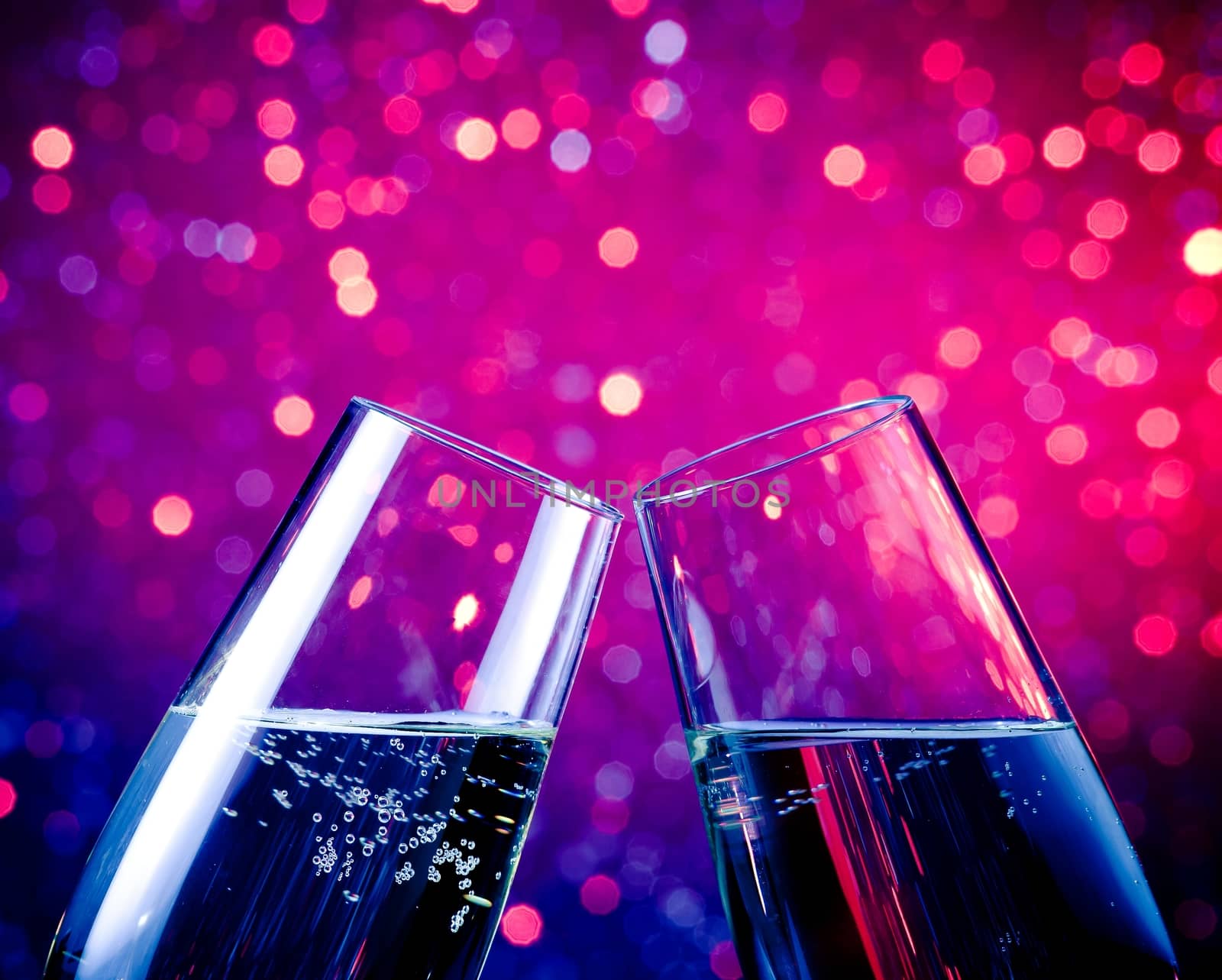 pair of champagne flutes with gold bubbles make cheers on blue tint light bokeh background with space for text
