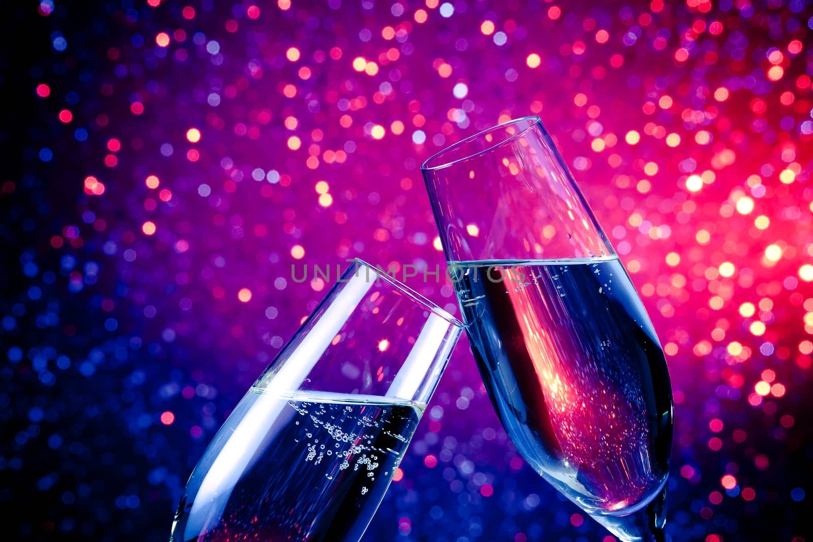 pair of champagne flutes with gold bubbles make cheers on blue tint light bokeh background