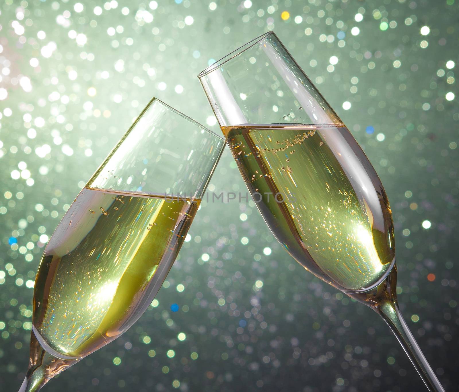 champagne flutes make cheers on green light bokeh background