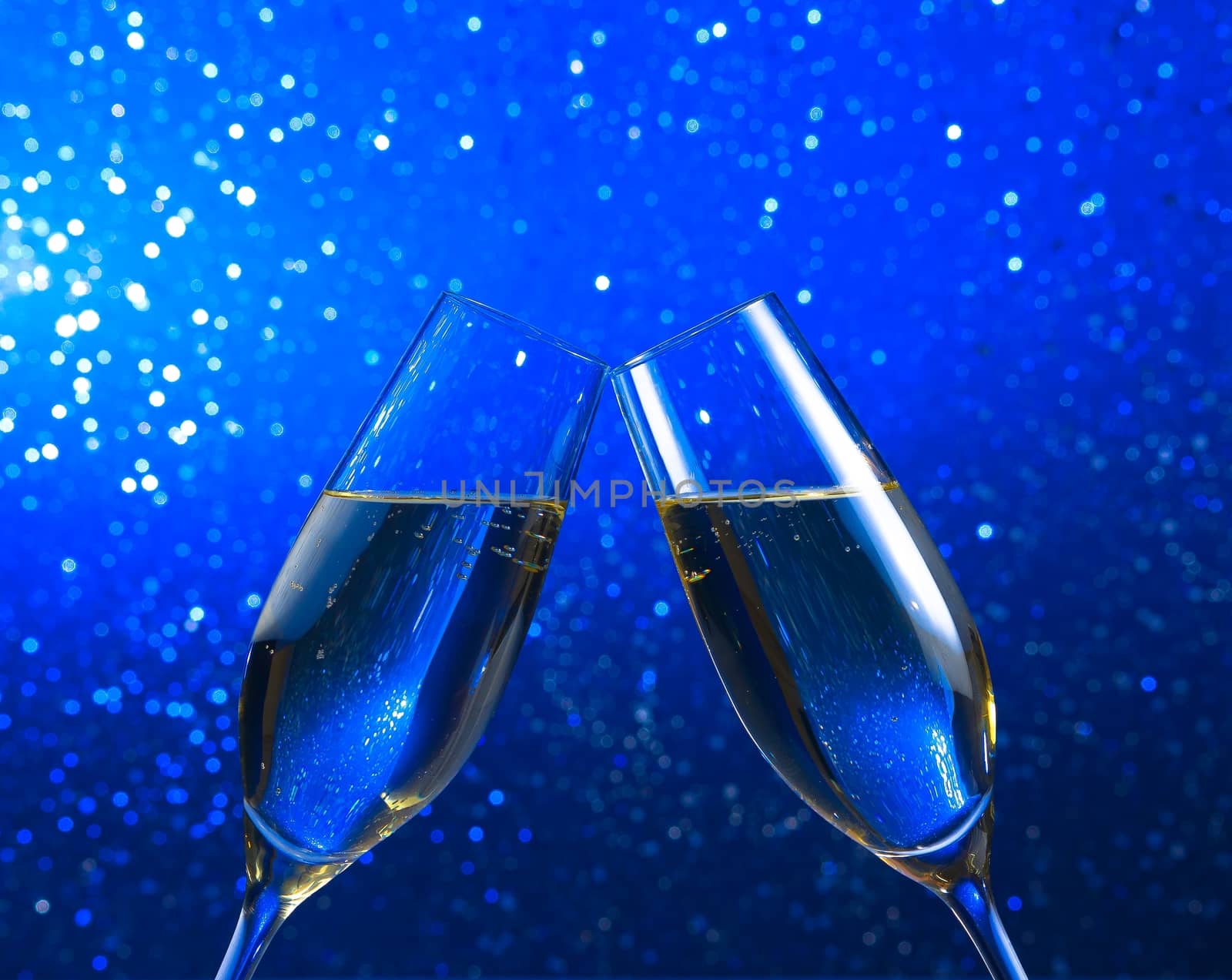 a pair of champagne flutes on blue light bokeh background by donfiore