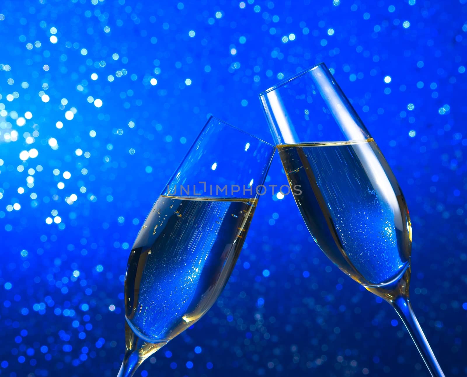 champagne flutes make cheers on blue light bokeh background with space for text