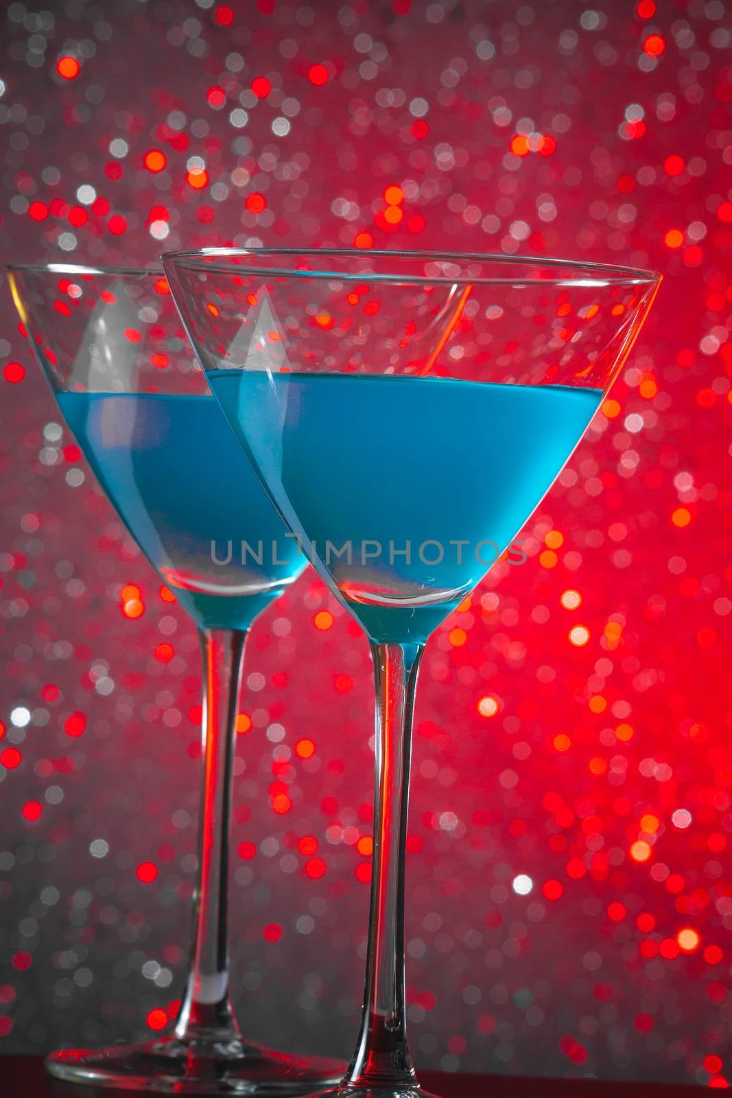 a pair of glasses of blue cocktail on table by donfiore