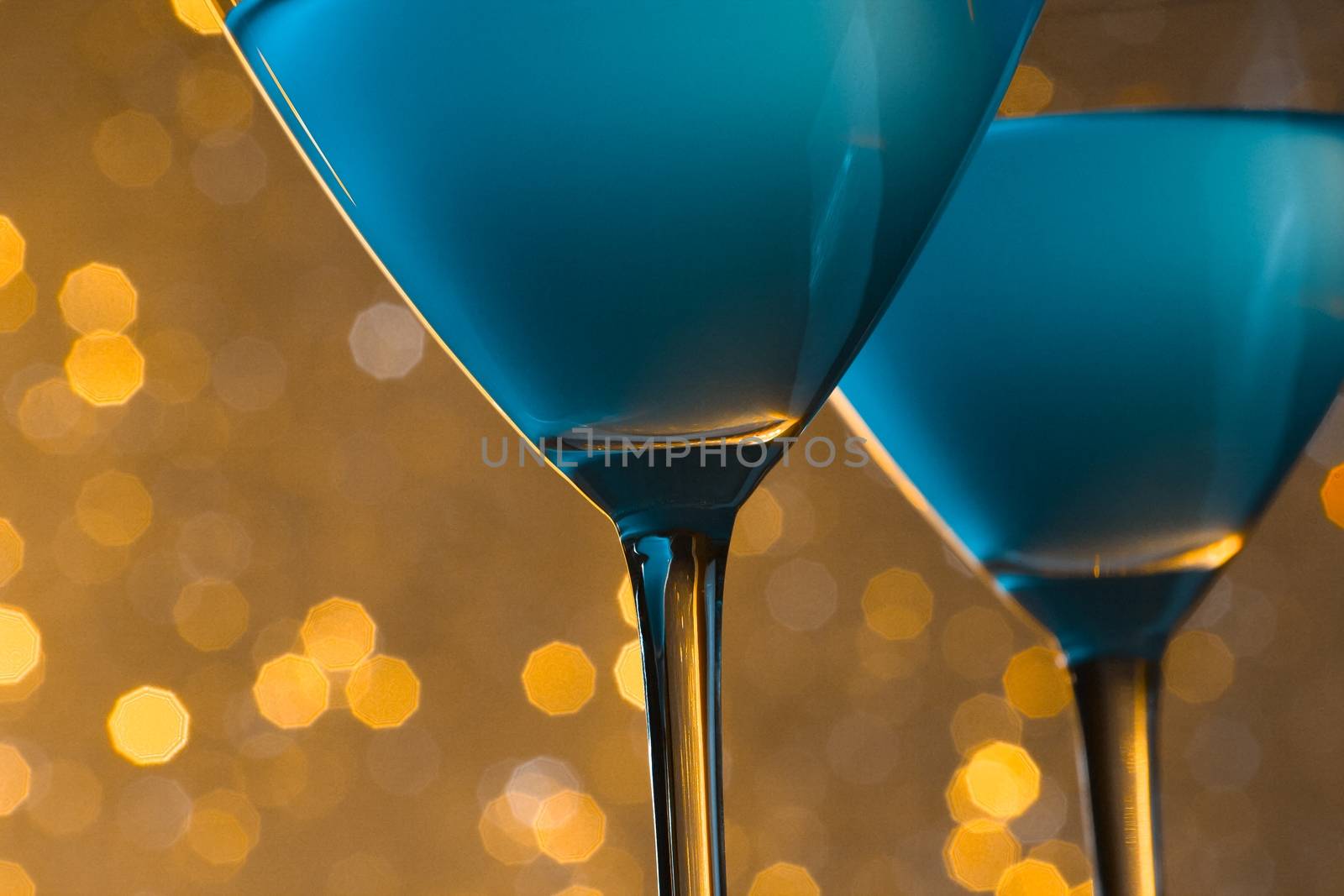 detail of glasses of blue cocktail on golden tint light bokeh background