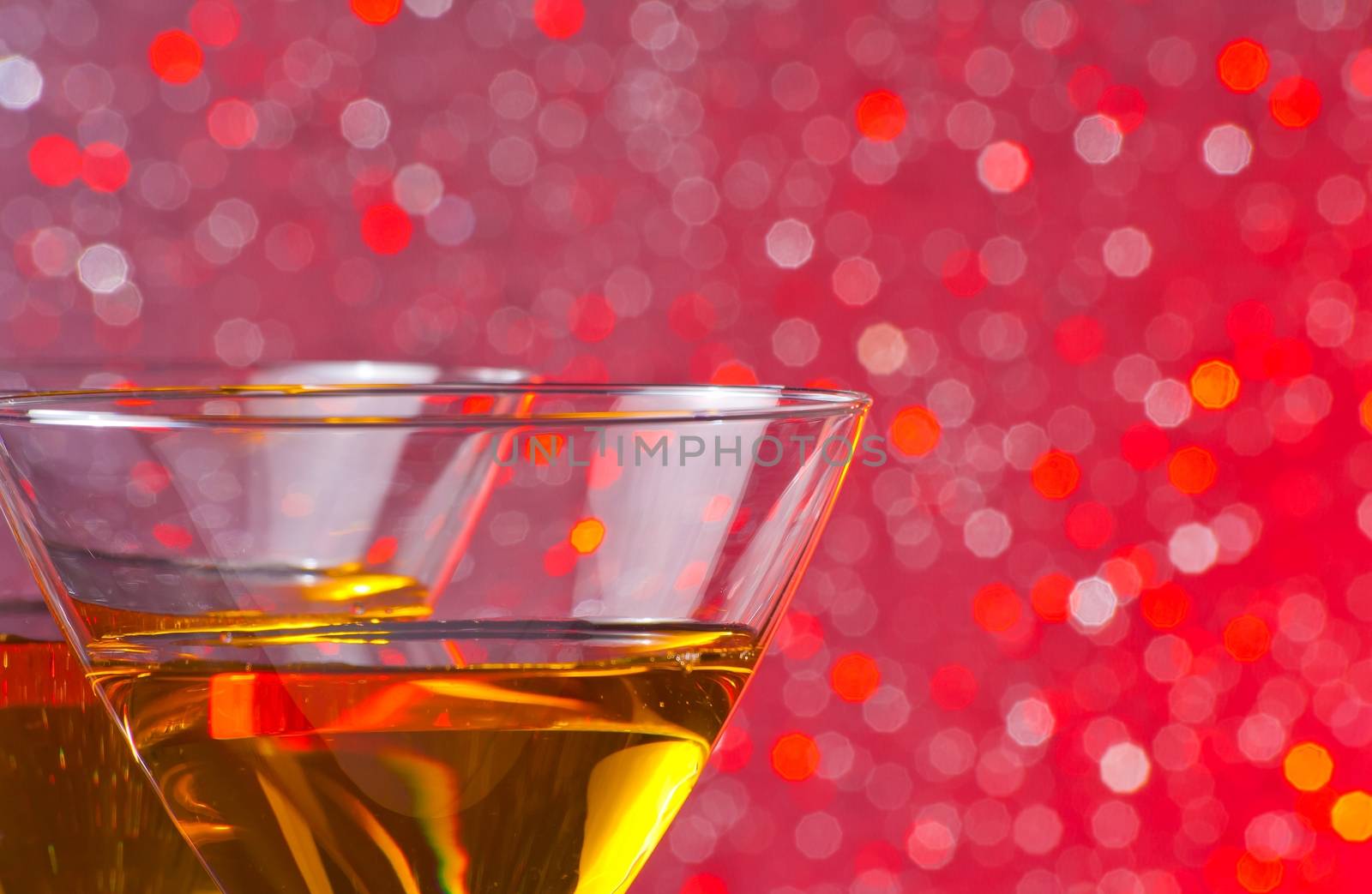 detail of two glasses of cocktail on red tint light bokeh background on bar table with space for text