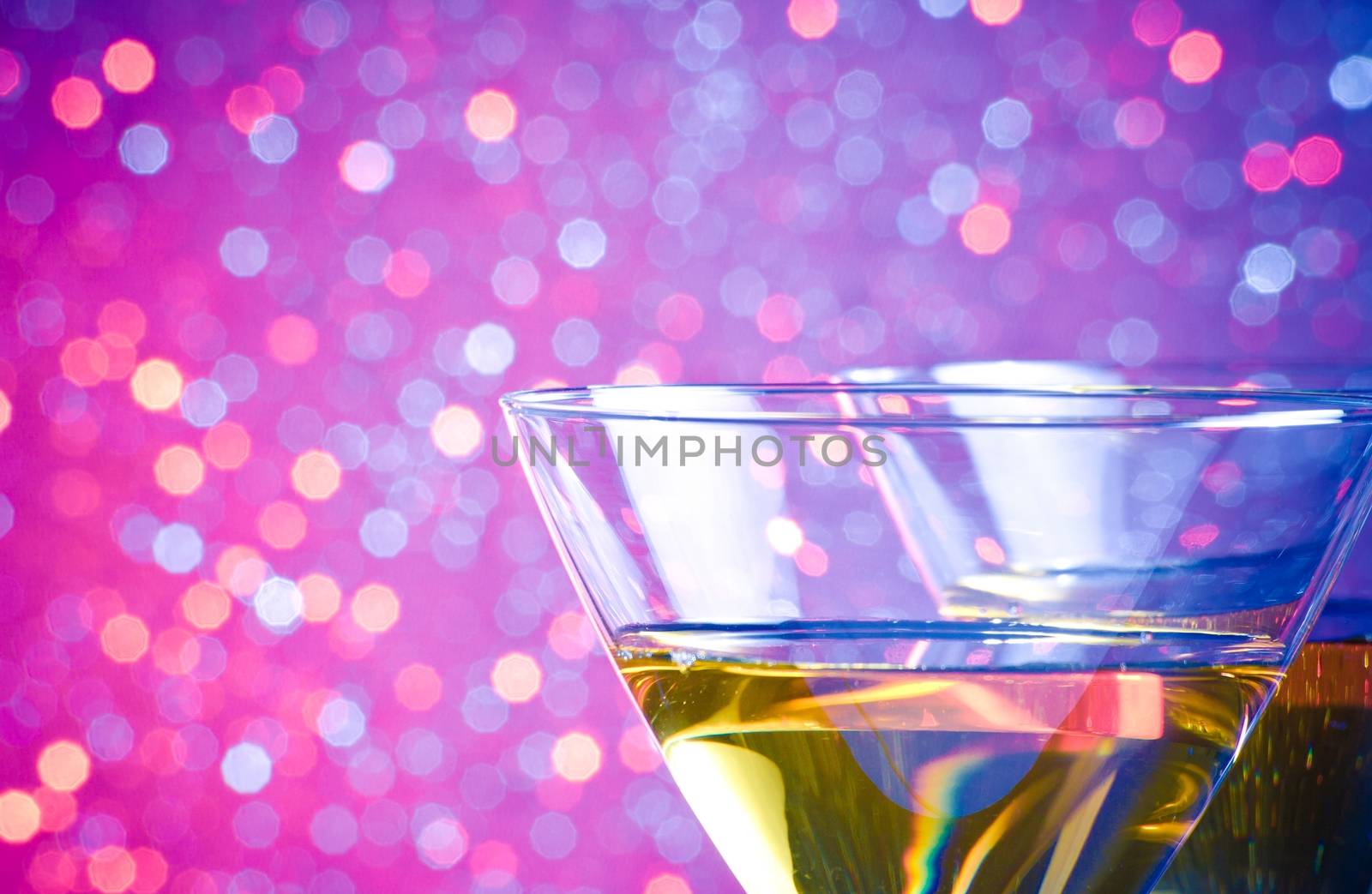 detail of two glasses of cocktail on blue and violet tint light bokeh background on bar table with space for text