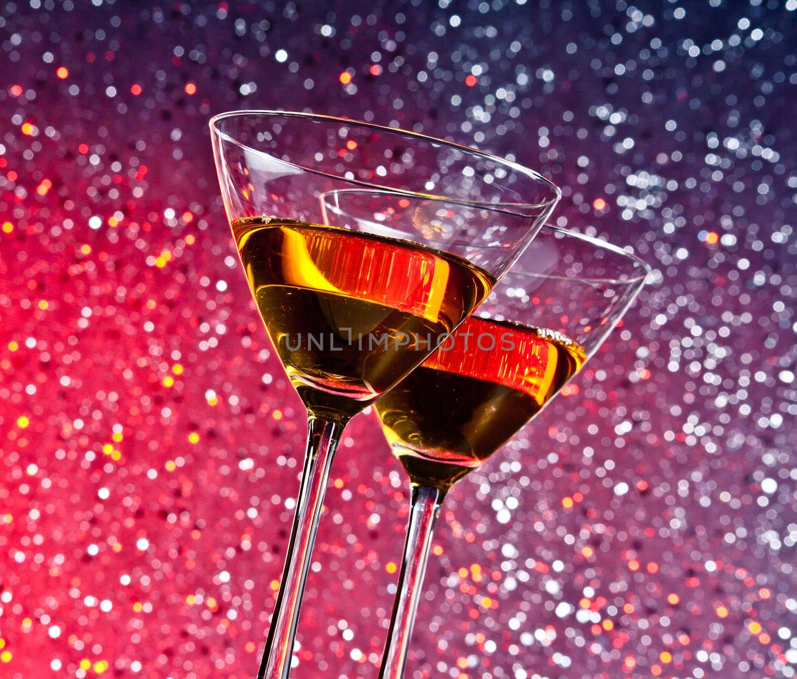 view from below of glasses of cocktail on red and violet tint light bokeh background on bar table