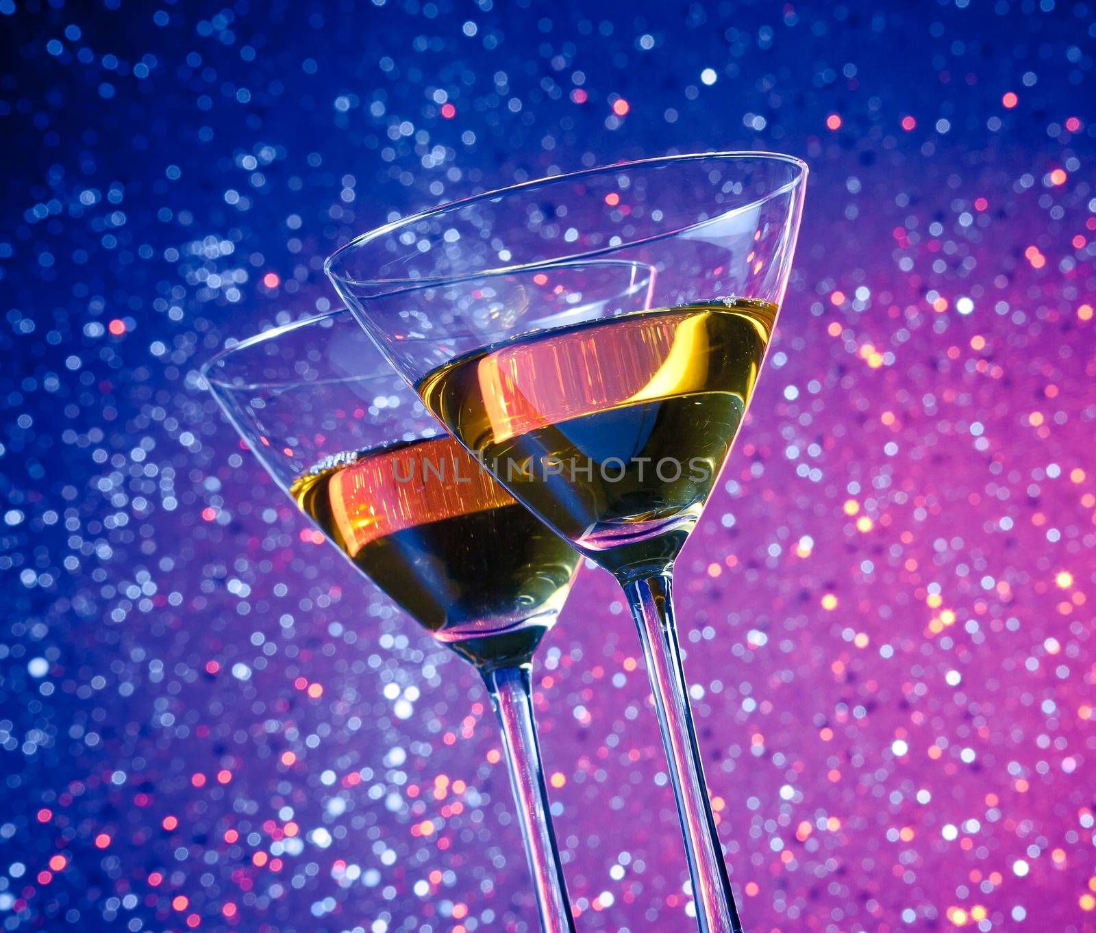 view from below of glasses of cocktail on red and violet tint light bokeh background on bar table