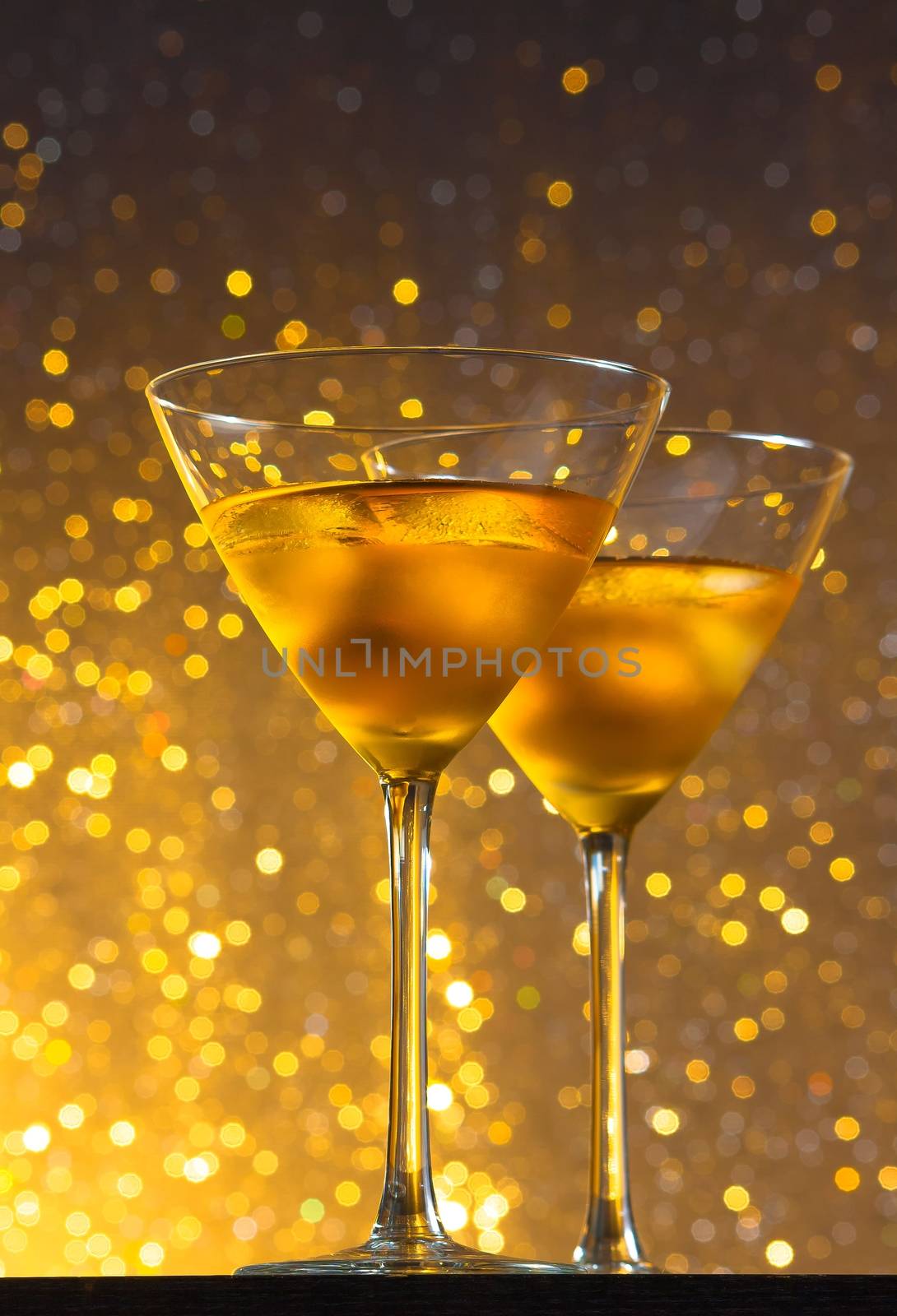 view from below of glasses of fresh cocktail with ice on golden tint light background on bar table