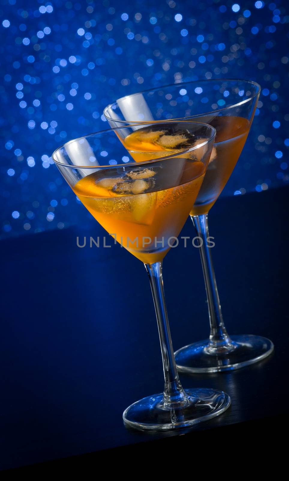 two glasses of  fresh cocktail with ice on blue tint light background on bar table