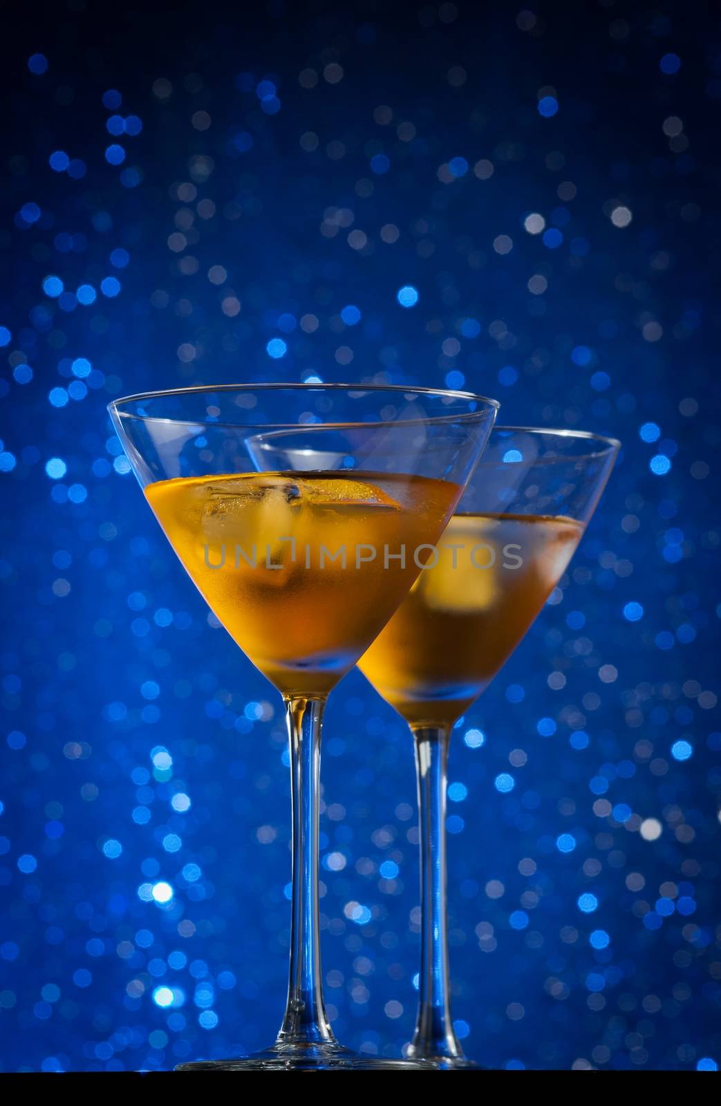 view from below of glasses of fresh cocktail with ice on blue tint light background on bar table